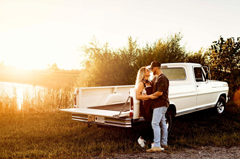 Liz beside a white vintage Ford pickup at golden hour