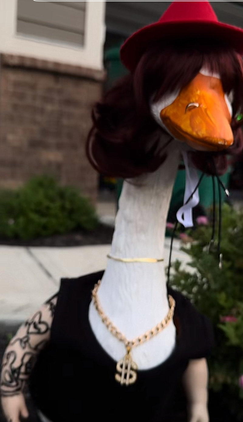 Lucy Goosey the porch goose in a red hat and gold chains